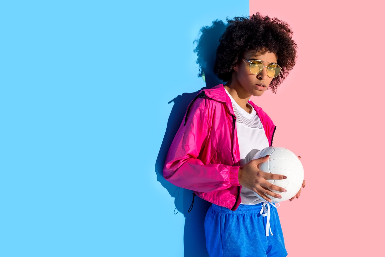 Young volleyball athlete with yellow glasses holding a white volleyball
